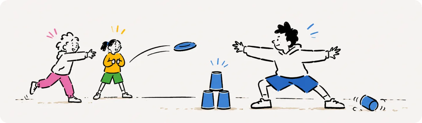 A kid throws a frisbee at a stack of blue cups while the defender spreads their arms wide and another kid cheers